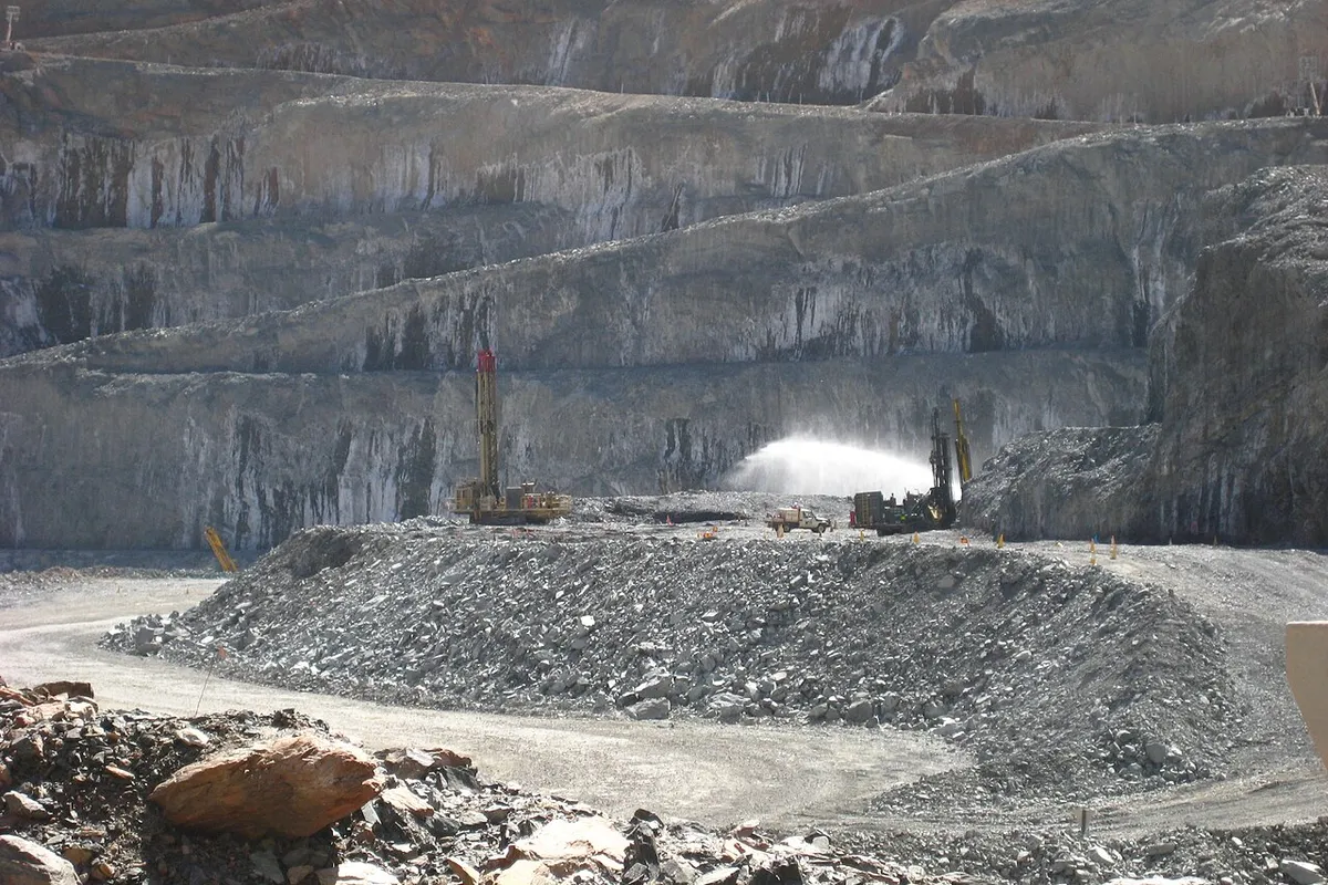Benched open pit at Sunrise Dam gold mine, Western Australia, with drill rigs working on the floor